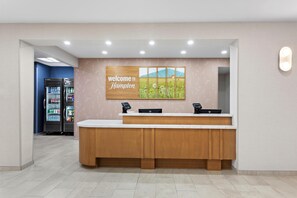 A reception area with a wooden counter, a welcome sign, and a refrigerator stocked with beverages.