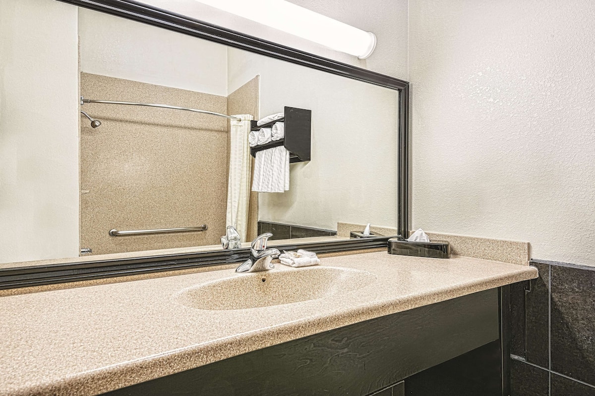 A bathroom with a large mirror, two sinks, and a towel rack.