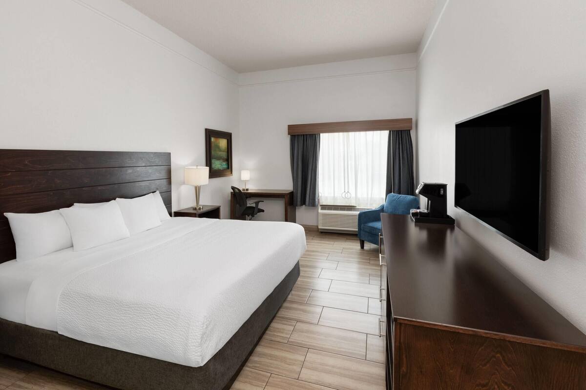 A hotel room with a large bed, a flat-screen TV, a desk, and a chair.