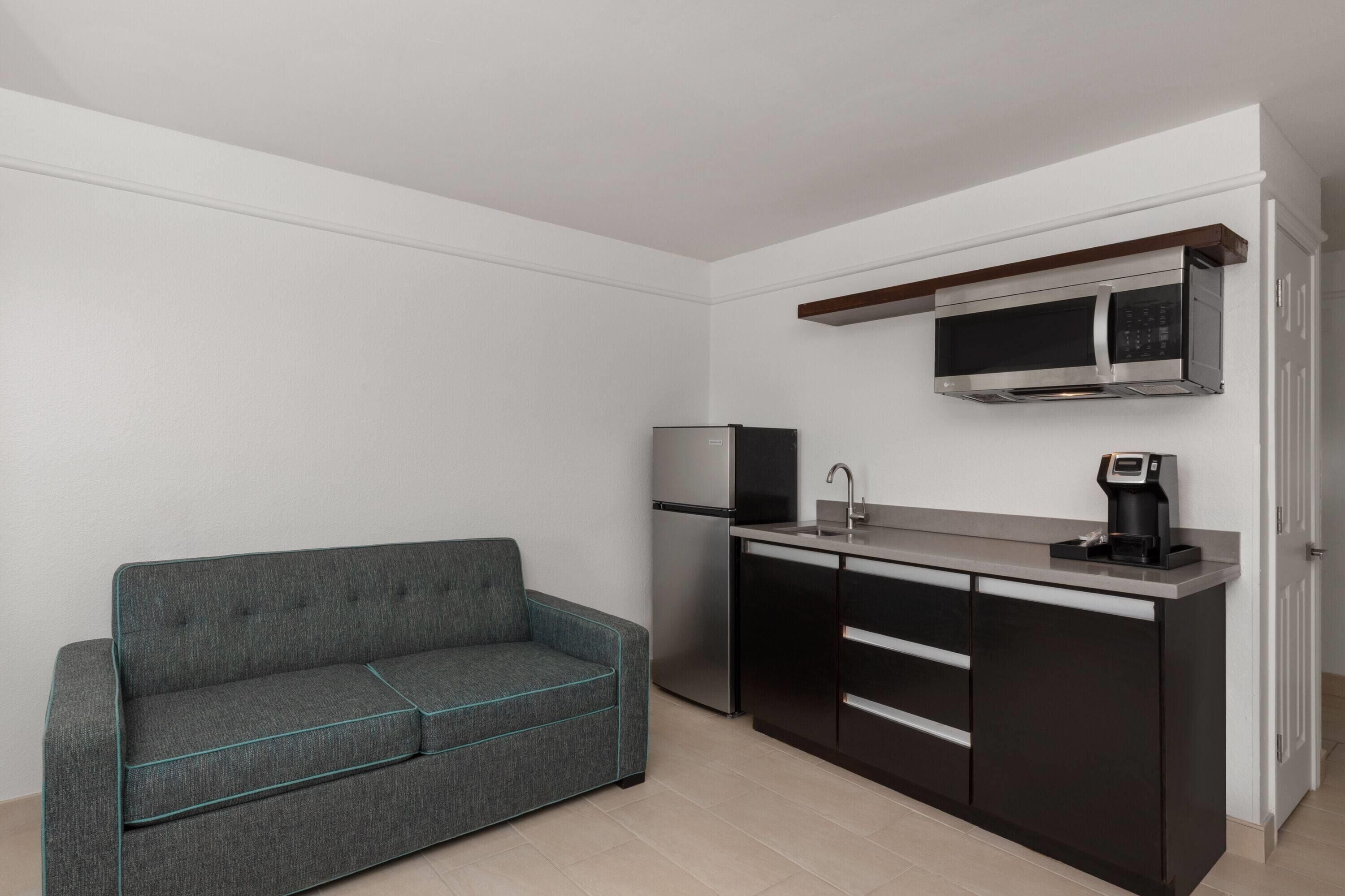 A compact kitchen with a microwave, coffee maker, and a built-in oven.