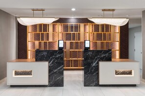 Balcão de recepção com tampos de mármore e painel de madeira ao fundo.