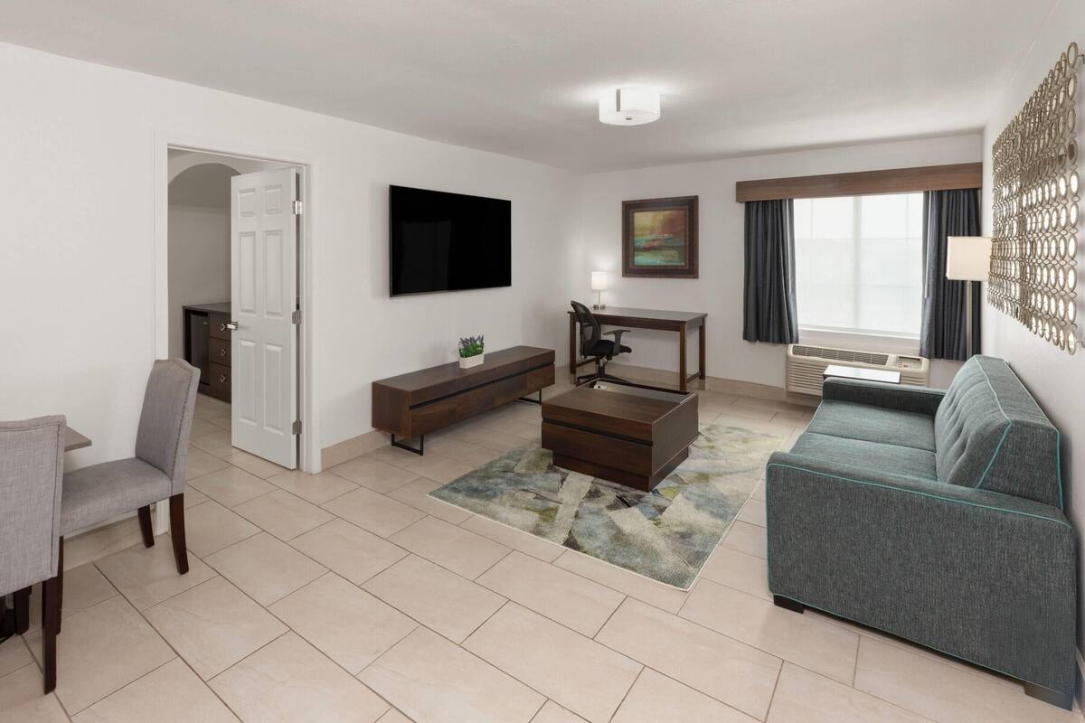 A modern living room with a sofa, a TV, a desk, and a chair.