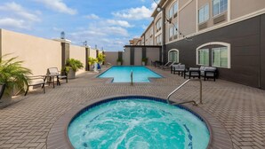 A swimming pool with a hot tub, lounge chairs, and potted plants. - La Quinta Inn & Suites by Wyndham Laredo Airport (Laredo)