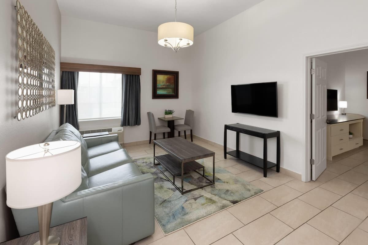 A modern living room with a sofa, coffee table, TV, and a dining area.