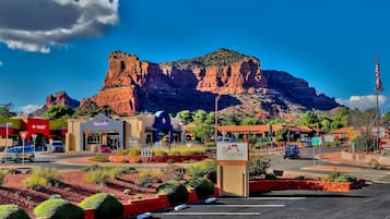 A hotel with a view of a mountain, a parking lot, and a road with cars.
