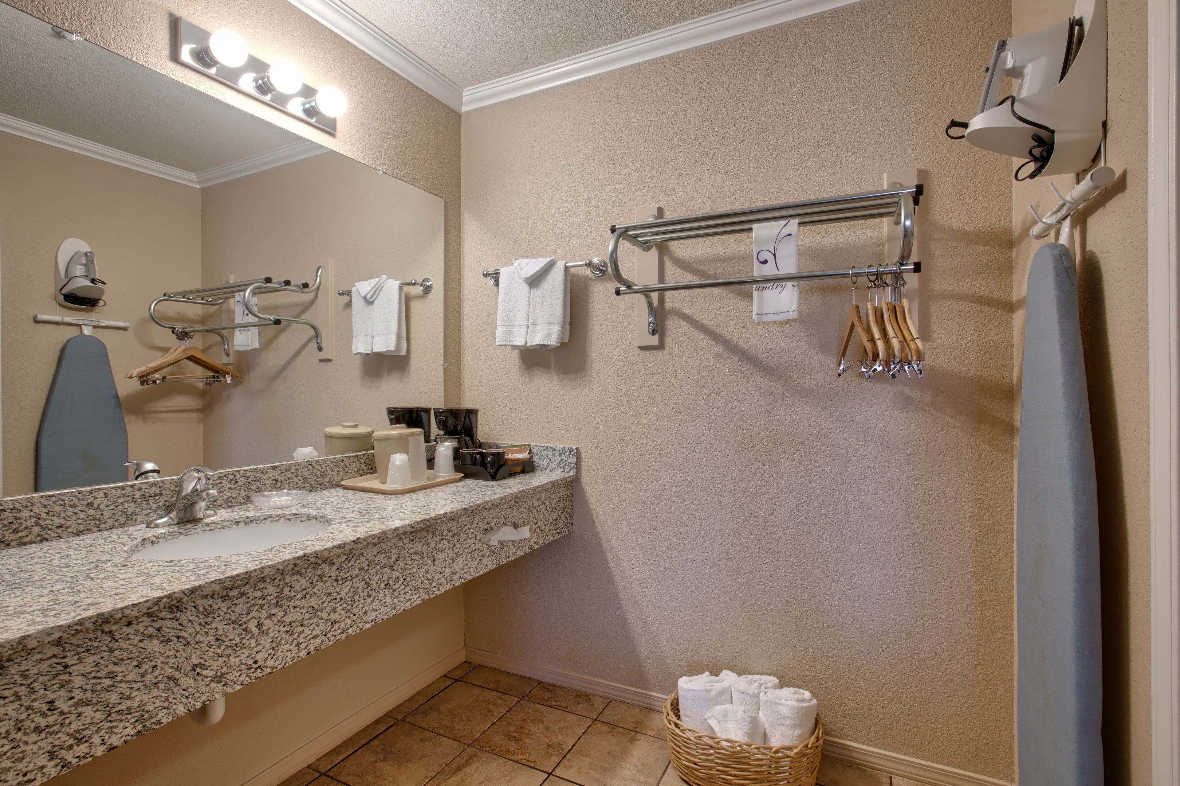 A bathroom with a granite sink, a mirror, a towel rack, and a shower area.