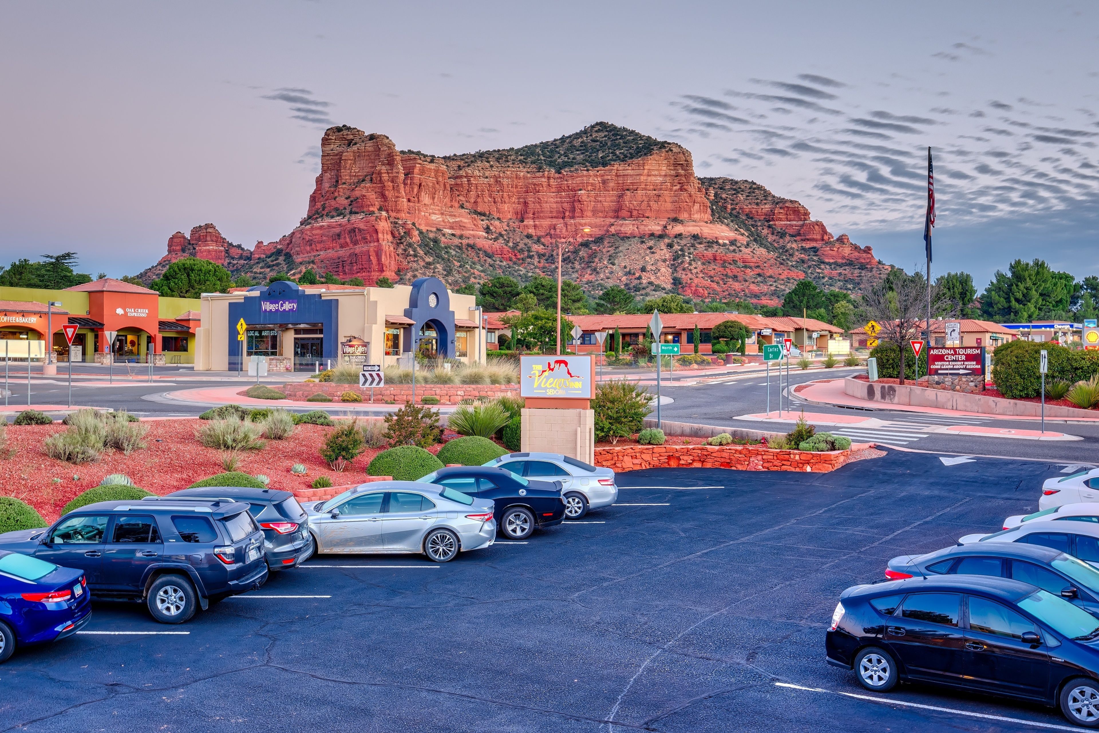 A parking lot with cars, a building with a blue sign, and a mountain in the background.