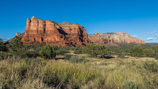 A large red rock formation with a clear blue sky.