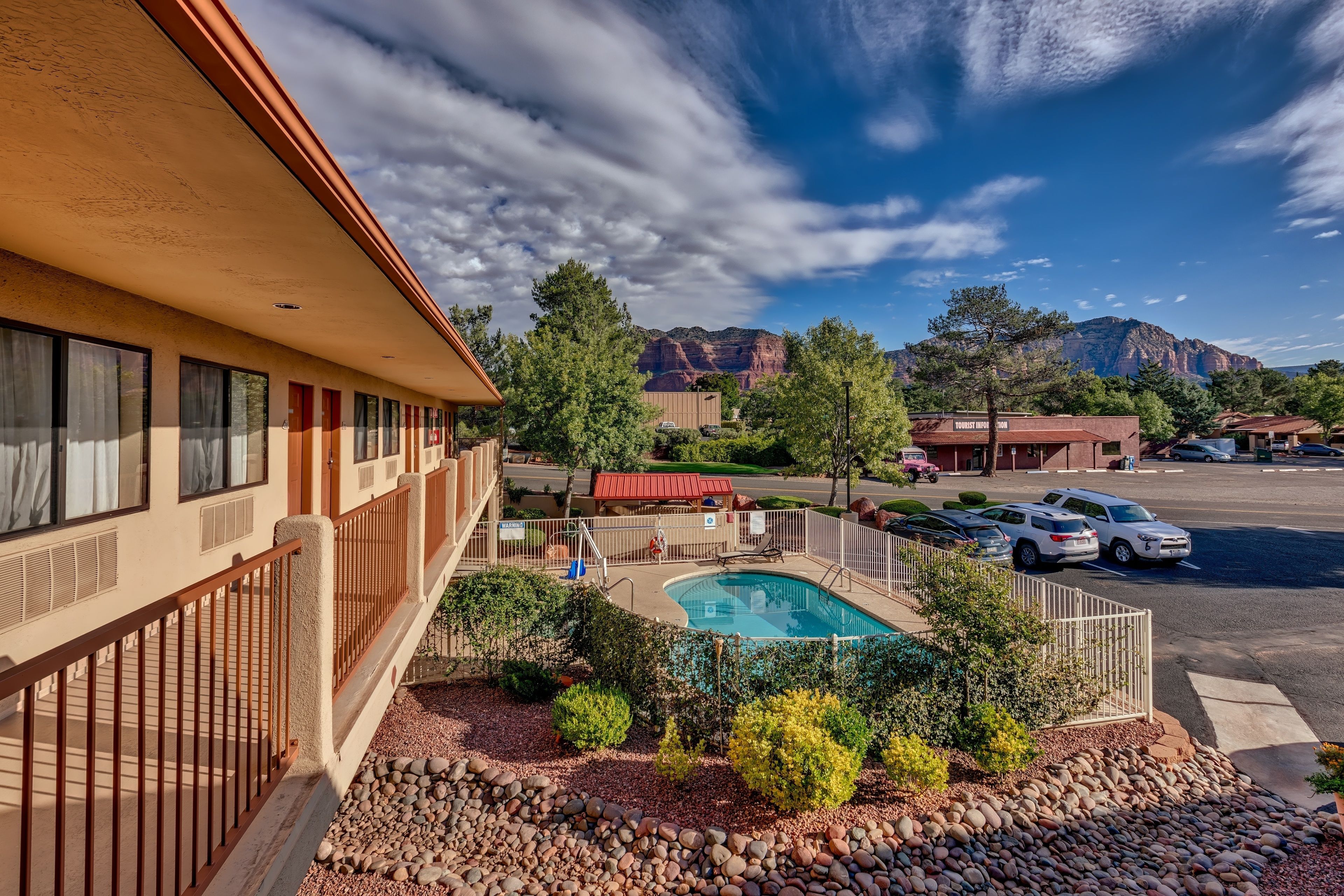 A hotel with a swimming pool, outdoor seating, and a mountain view.