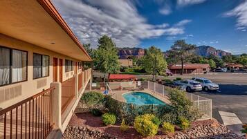 A hotel with a swimming pool, outdoor seating, and a mountain view.