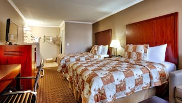 A hotel room with two beds, a desk, a chair, a lamp, and a mirror.