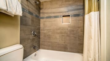 Un baño con bañera, inodoro y ducha.
