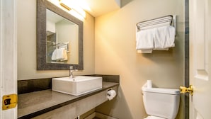 A bathroom with a sink, mirror, toilet, and towel rack. - Regency Inn & Suites (Downey)