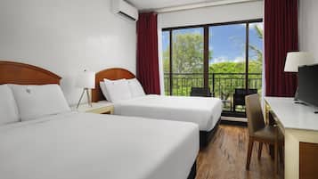 A hotel room with two beds, a desk, a chair, and a large window with a balcony view.