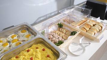 A buffet with various food items including eggs, scrambled eggs, muffins, and cookies.