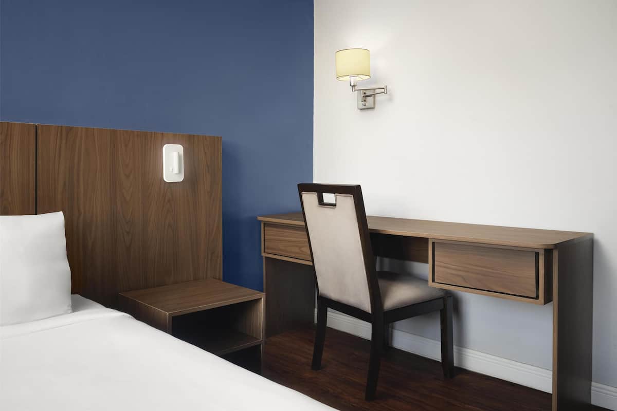 Ein Hotelzimmer mit Bett, Schreibtisch, Stuhl und Nachttisch.