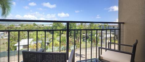 Un balcone con vista su una zona residenziale, tra case e vegetazione.