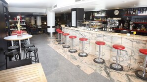 A bar area with a marble countertop, red bar stools, and a variety of liquor bottles. - Hotel Real Lleida (Lleida)
