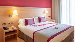 A hotel room with a large bed, two bedside tables, a nightstand, a lamp, and a window with curtains. - Hotel Real Lleida (Lleida)