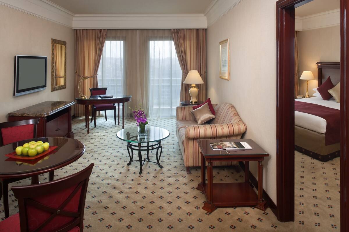 A hotel room with a dining area, a sofa, a bed, and a TV.