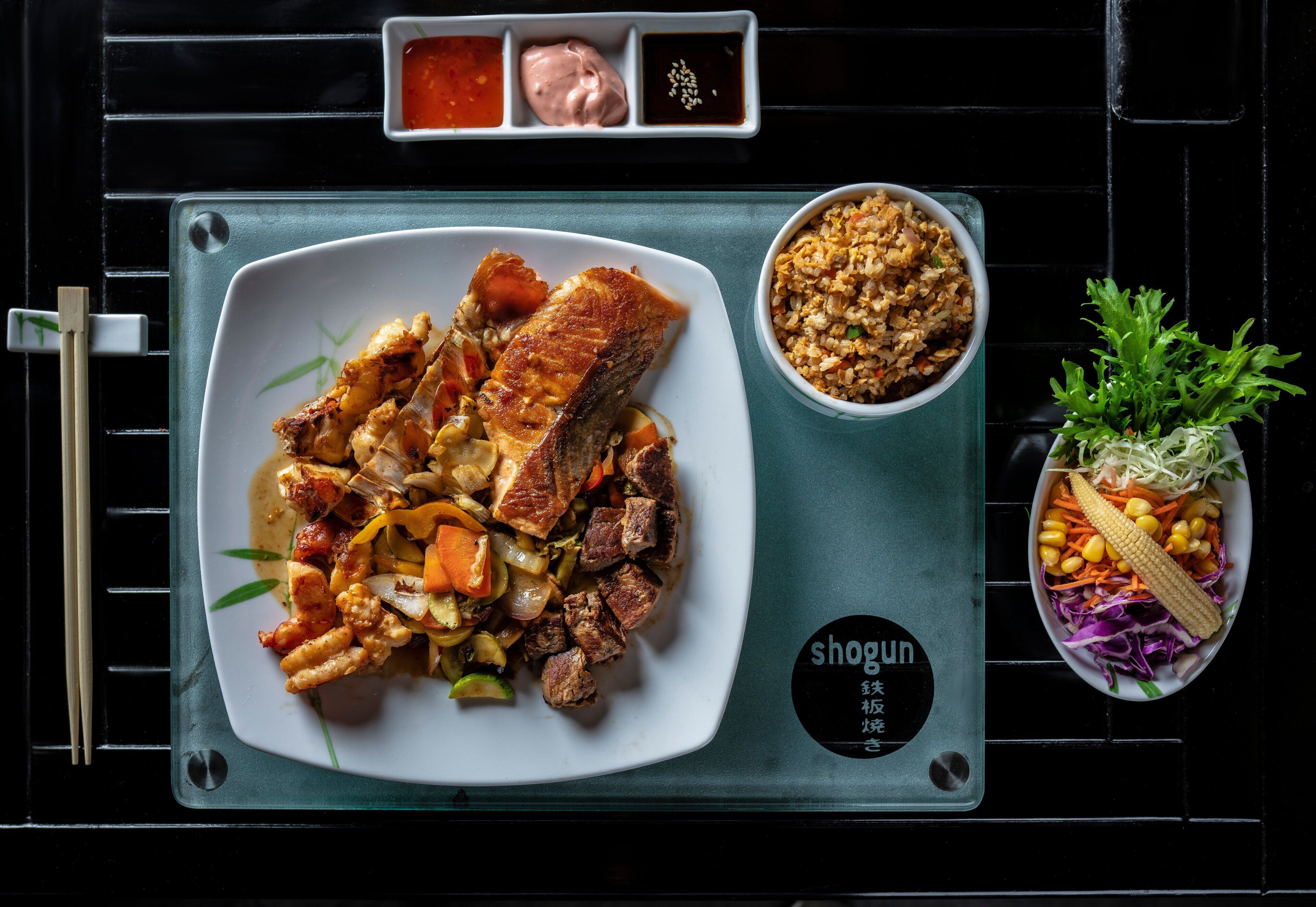 A meal with various dishes on a tray, including a plate of meat, a bowl of rice, and a side salad.