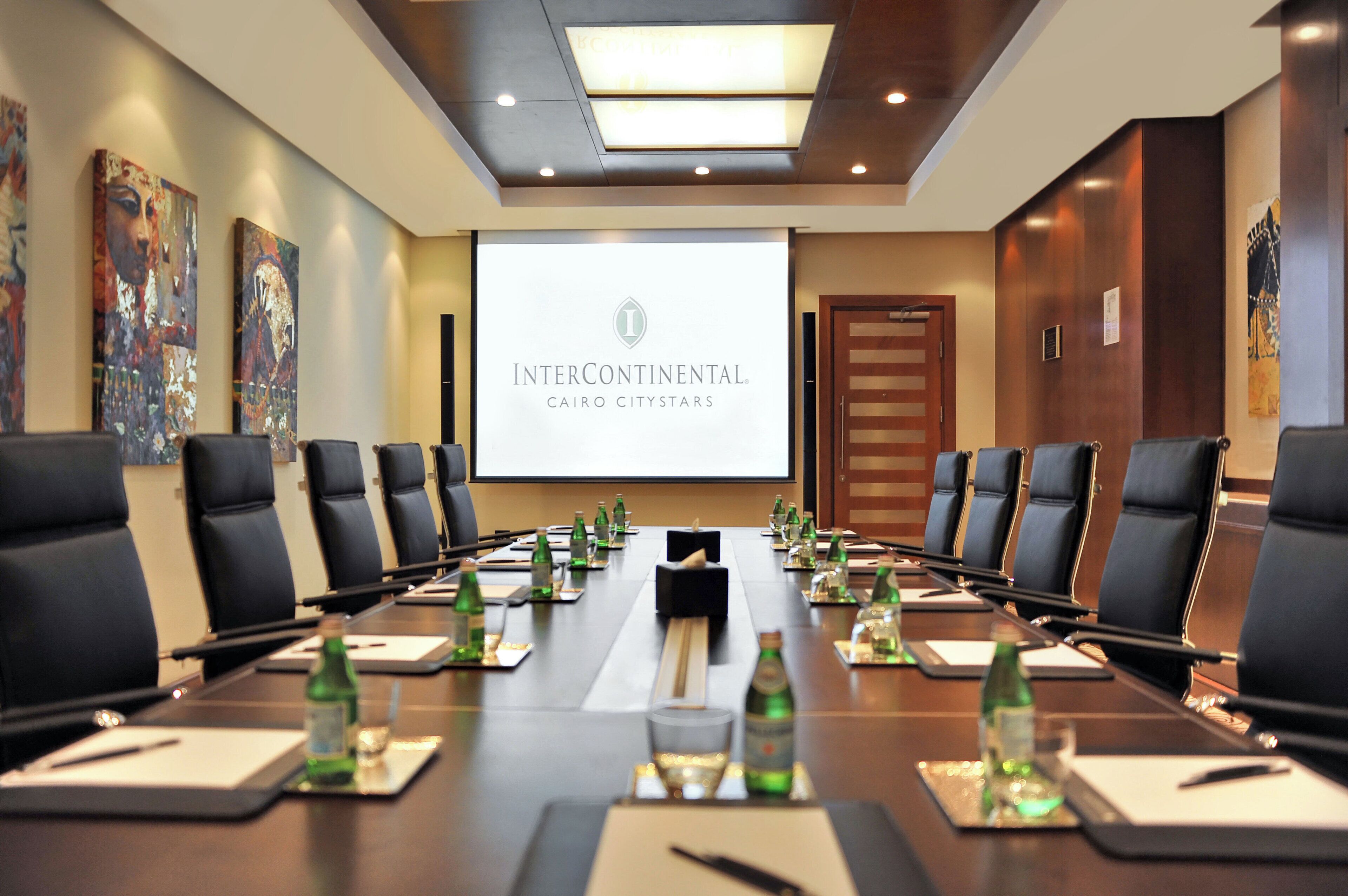 A conference room with a long table, chairs, and a projector screen displaying 'InterContinental Cairo Citystars'.