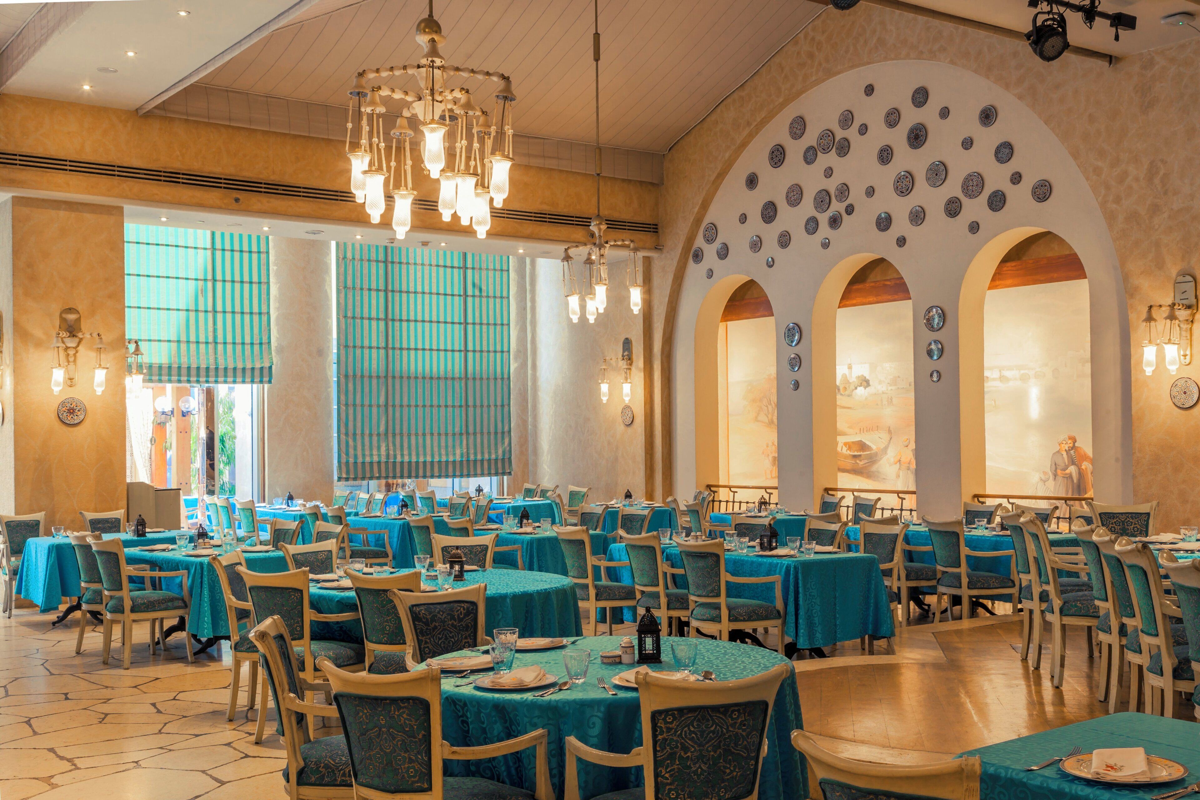 Un restaurant doté de nombreuses tables, de chaises et d’un grand lustre.