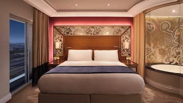 A hotel room with a large bed, a view of the city, and a decorative wall.