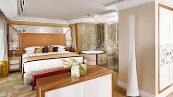 A modern hotel room with a large bed, a bedside table, a vanity with a mirror, and a round bathtub.