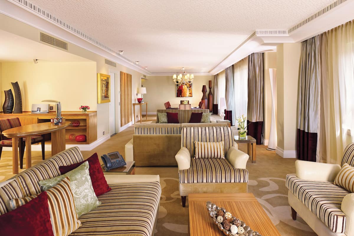 A spacious living room with striped sofas, a wooden coffee table, and a dining area with a table and chairs.