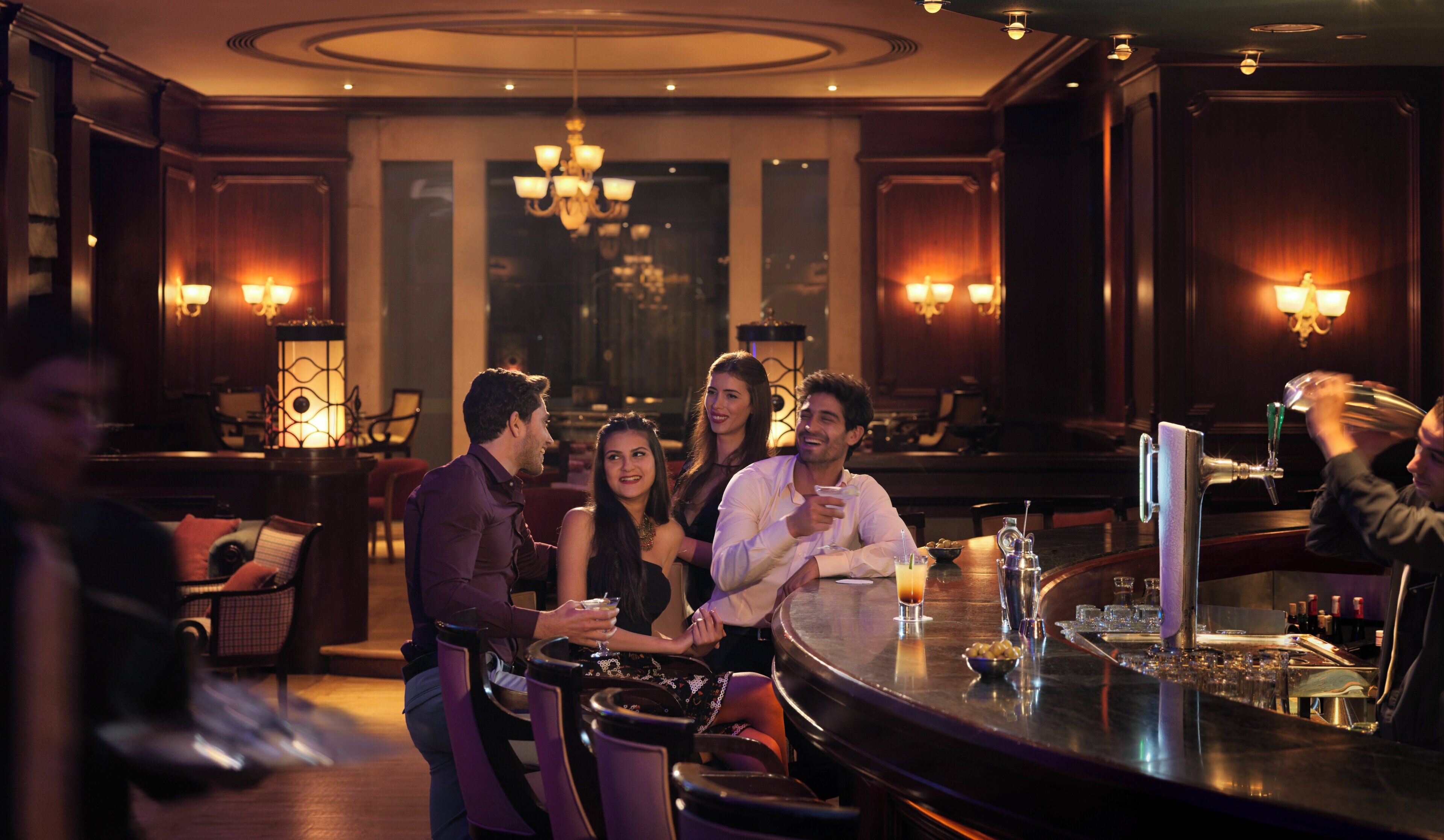 A bar area with a round table, chairs, and a bartender.