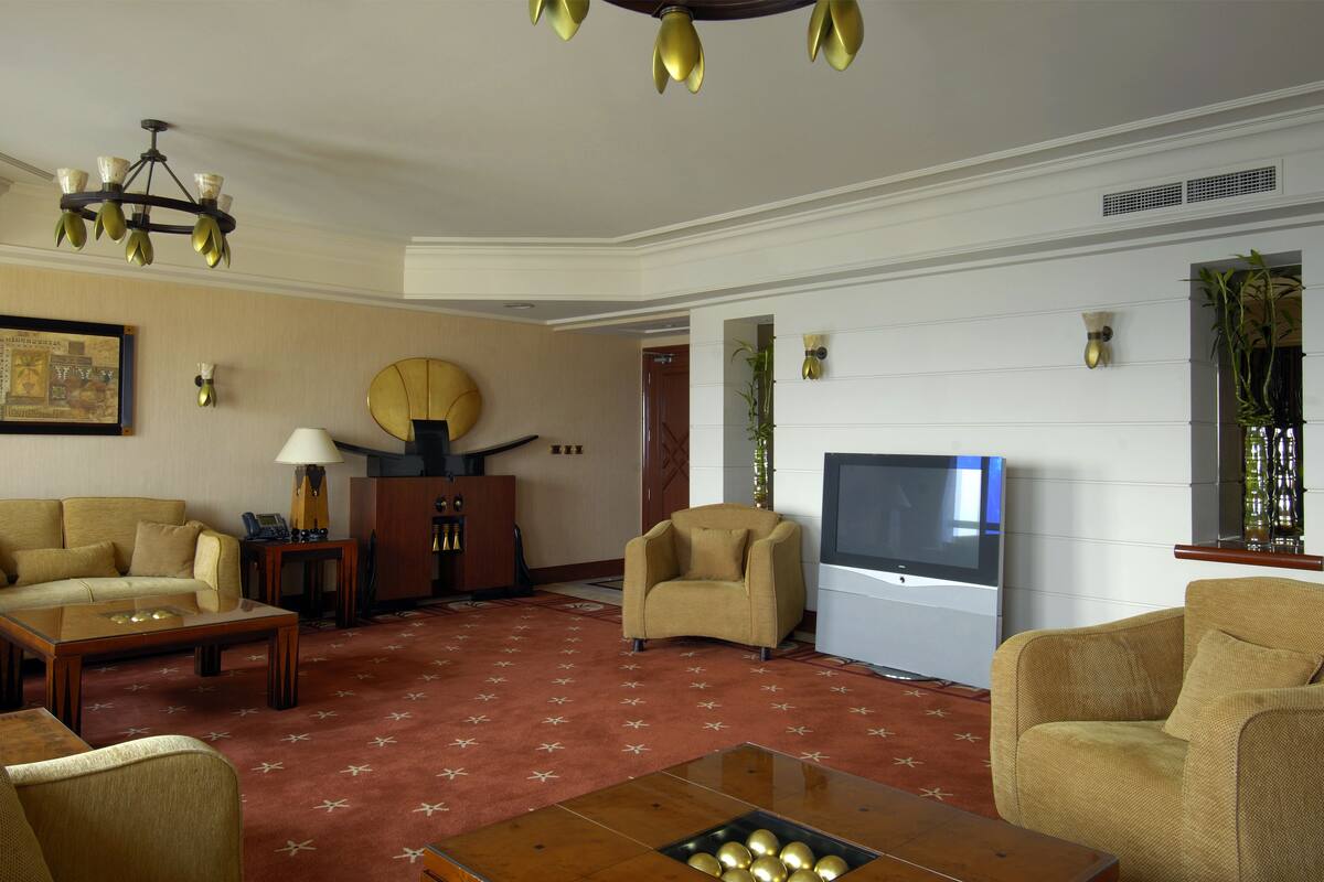 A living room with a sofa, armchairs, a coffee table, a TV, and a decorative chandelier.