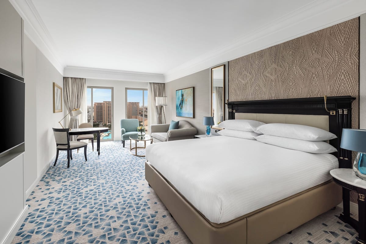 A hotel room with a large bed, a desk, a chair, and a view of the city.