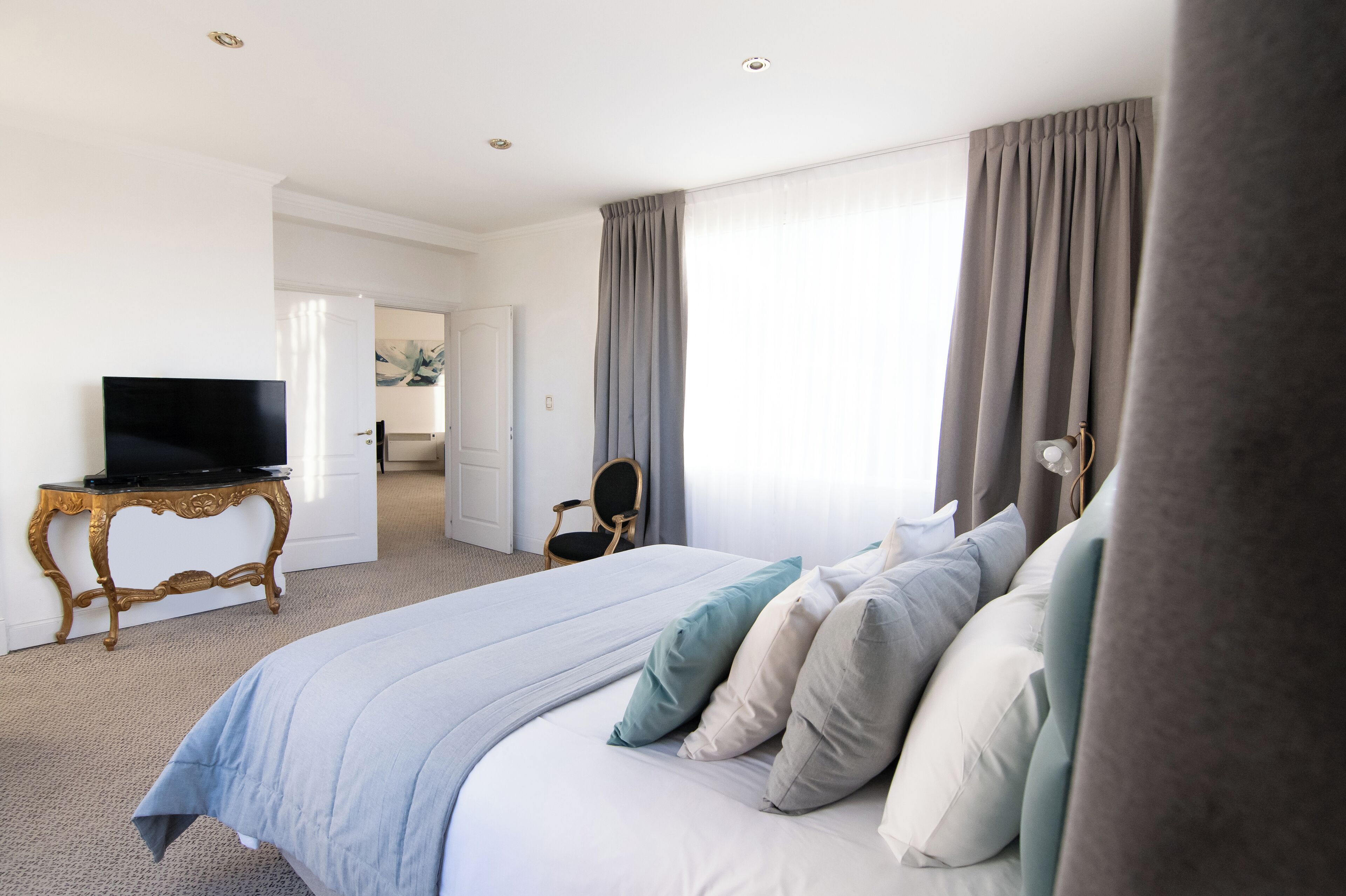 A hotel room with a large bed, a television on a small table, and a chair.