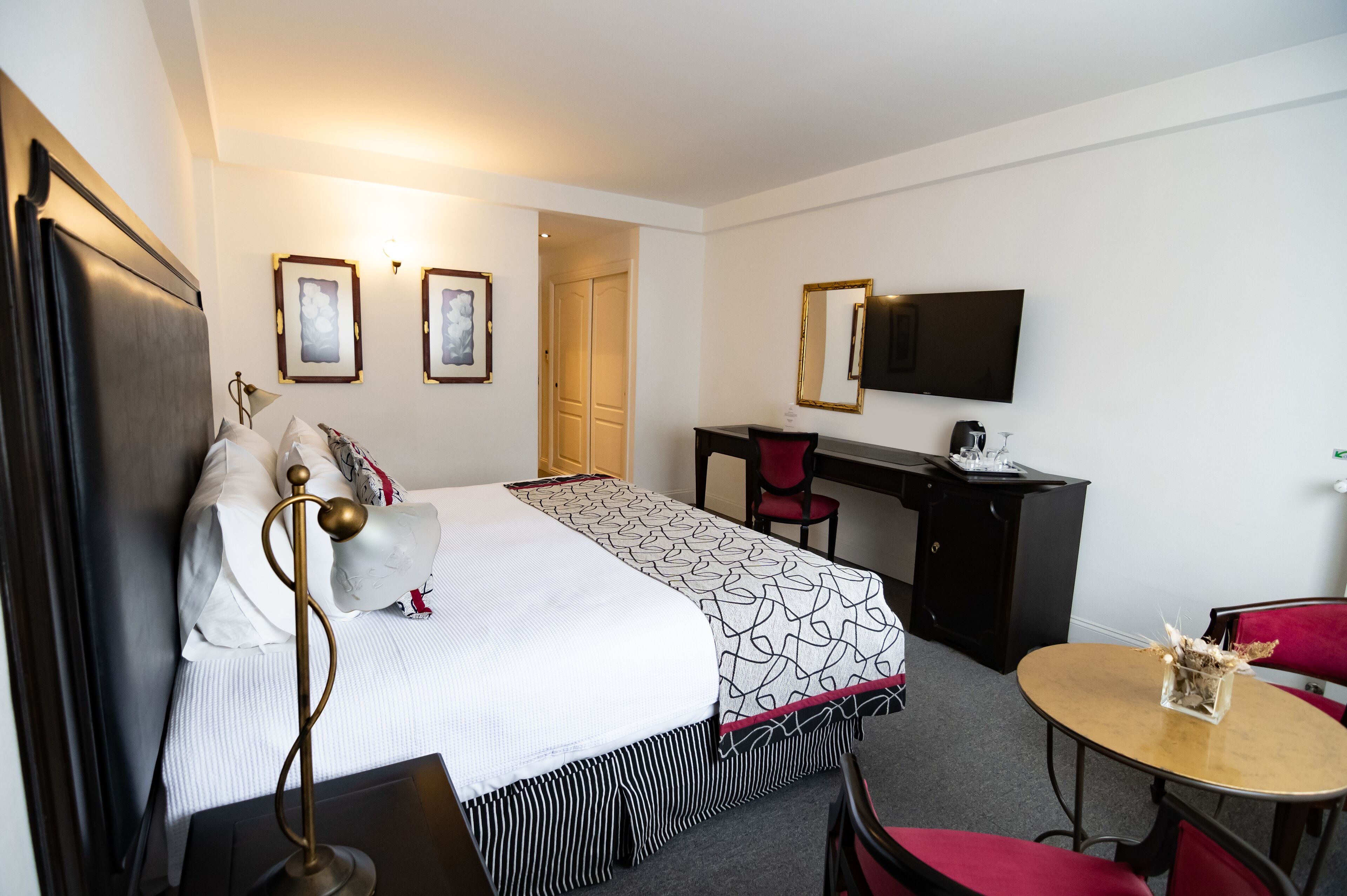 Una habitación de hotel con cama, escritorio, silla y televisor.