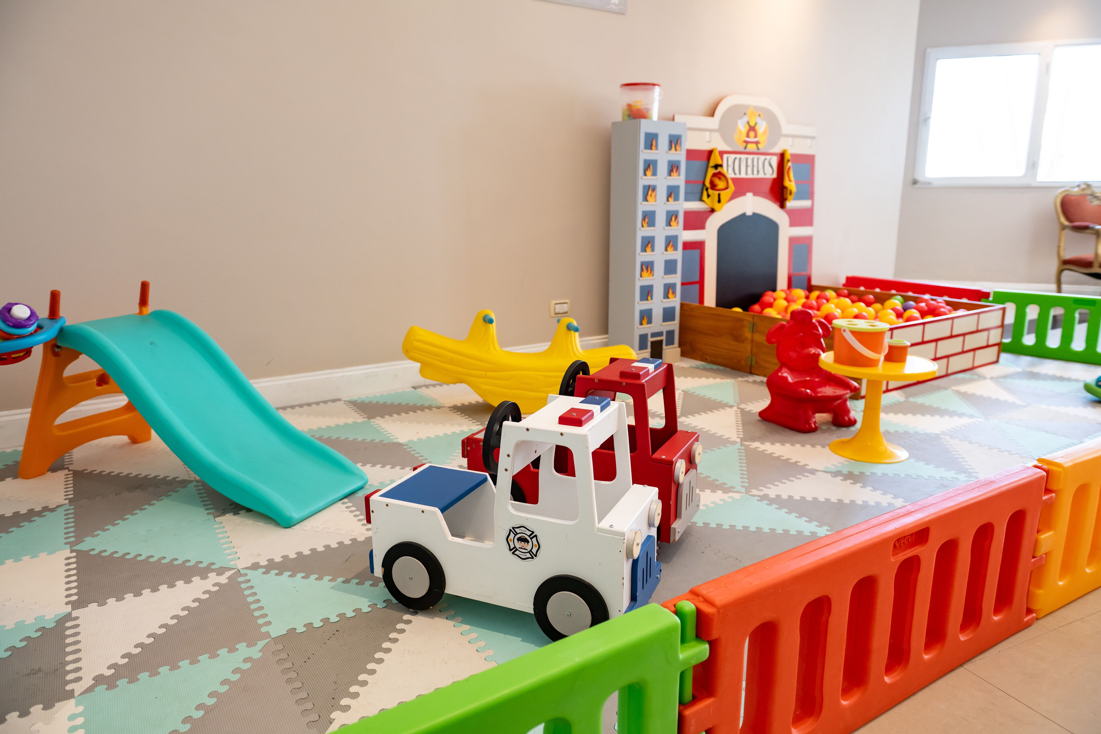 A play area with a slide, toy vehicles, and a ball pit.