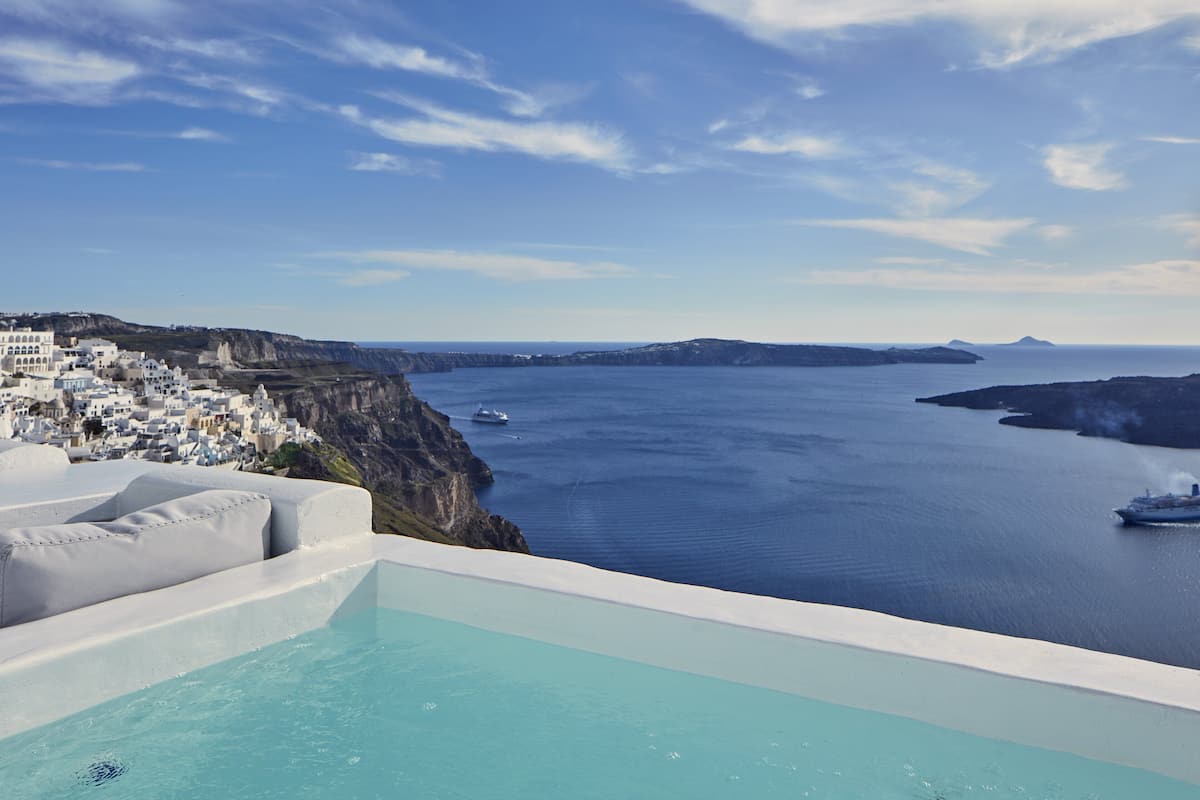 A seaside view with a pool overlooking a coastal town and the sea.