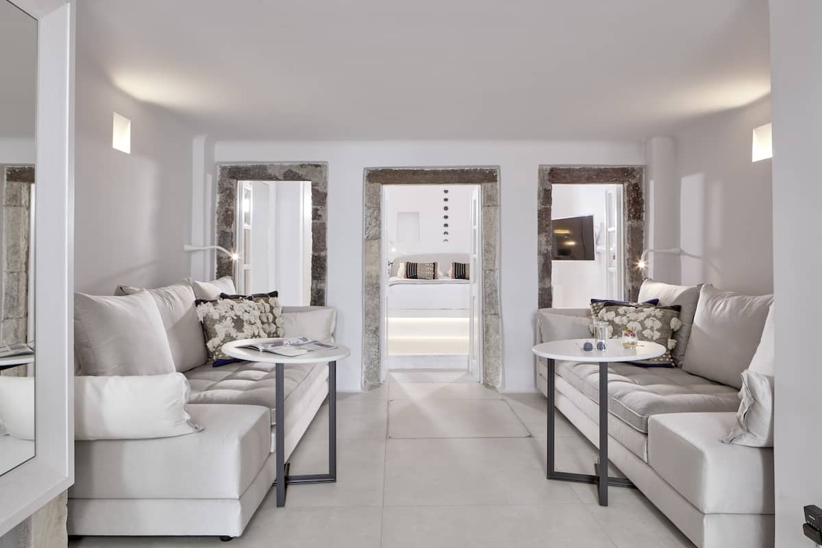 A modern hotel room with two sofas, a small round table, and a large mirror.