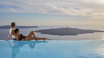 Relax by the serene infinity pool overlooking a tranquil body of water.