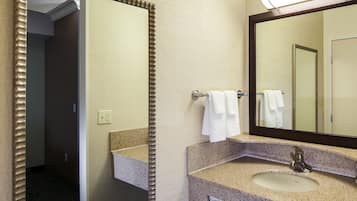A hotel bathroom with a large mirror, a sink, and a towel rack.