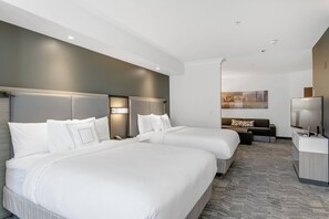 Una habitación de hotel con dos camas grandes, un sofá, un televisor y un escritorio.