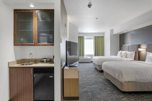 Una habitación de hotel con kitchenette, televisor, dos camas y baño.