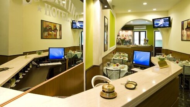 A hotel reception area with a counter, computers, and a television screen. - Hotel Sabatino (Milan)