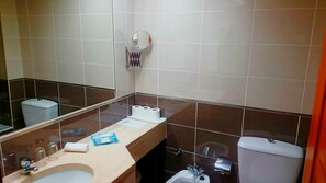 Un baño con lavamanos, espejo, inodoro y un perchero para toallas.