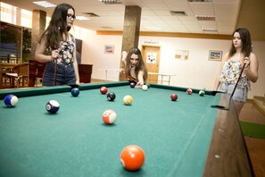 A pool table with balls in a room with a wooden floor, a door, and a bench. - Baia Cristal Beach & Spa Resort (Lagoa)