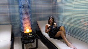 A room with a massage chair, a table with a heated stone, and a blue-tiled wall. - Baia Cristal Beach & Spa Resort (Lagoa)