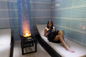 A room with a massage chair, a table with a heated stone, and a blue-tiled wall. - Baia Cristal Beach & Spa Resort (Lagoa)