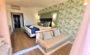 Habitación de hotel con cama, sofá, espejo y pared con diseño de hojas.