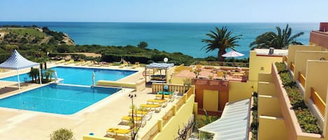 Una piscina techada, una piscina al aire libre, sombrillas