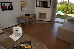 Una sala de estar con chimenea, un comedor con mesa y sillas, y vista al jardín a través de una puerta corredera.